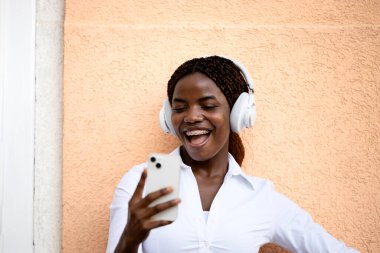 Mutlu gülümseyen Afrikalı kadın akıllı telefon kullanıyor ve gülüyor..