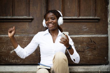 Mutlu gülümseyen Afrikalı kadın müzikten ve şarkıdan hoşlanıyor.