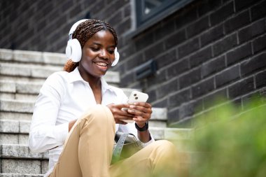 Sokakta akıllı telefon kullanan güzel siyah bir kadın..