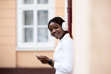 Mutlu gülümseyen Afrikalı kadın akıllı telefon kullanıyor ve gülüyor..