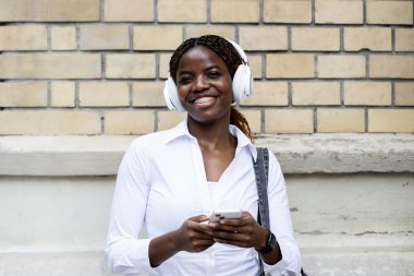 Akıllı telefonlu mutlu gülümseyen zenci kadın portresi.