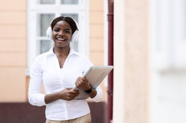 Güzel Afrikalı kadın dizüstü bilgisayarını tutuyor ve kameraya bakıyor..