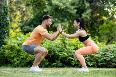 Spor yapan ve parkta çömelen insanlar..