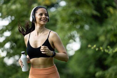 Parkta koşan güzel, gülümseyen esmer, spor elbiseli kadın..