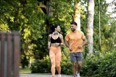 Formda ve sağlıklı çiftler birlikte antrenman yapıyor ve parkta koşuyor..