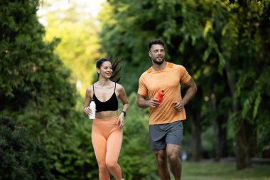 Formda ve sağlıklı insanlar birlikte antrenman yapıyor ve parkta koşuyor..