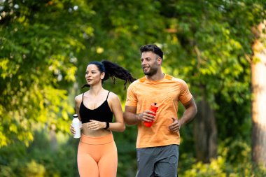 Formda ve sağlıklı beyaz insanlar birlikte antrenman yapıyor ve parkta koşuyor..