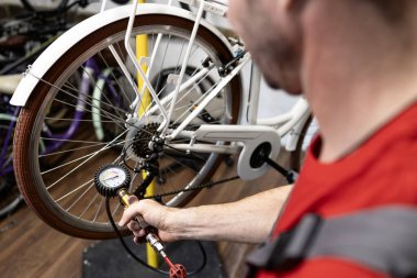 Profesyonel bisiklet tamircisi atölyedeki bisiklet lastiğinin basıncını kontrol ediyor..