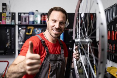 Bisiklet direksiyonunda duran ve baş parmağını kaldıran deneyimli bisiklet tamircisinin portresi.