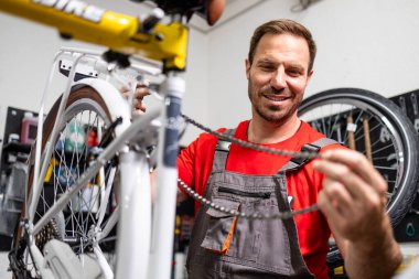 Tecrübeli bisiklet tamircisi bisiklet dükkanında dişli zinciri tamir ediyor..