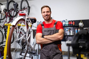 Kollarını kavuşturmuş beyaz bisiklet tamircisinin portresi..