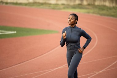 Siyahi kadın maraton koşucusu yarışmaya hazırlanıyor. Pistte koşan ve maratona hazırlanan bayan sporcu.