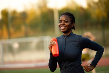 Gülümseyen siyah bayan sporcu dışarıda koşuyor ve antrenman yapıyor..