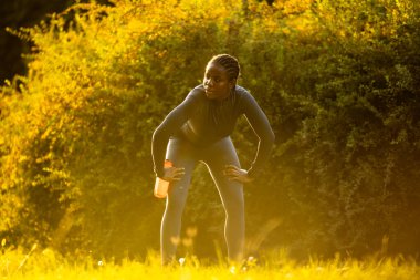 Gün batımında parkta koşan siyah bayan sporcu.