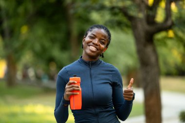 Gülümseyen bayan sporcu dışarıda başparmak kaldırıyor..