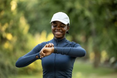 Sporcu kadın kalp atışlarını kontrol ediyor ve akıllı saatle mesafeyi koşuyor..