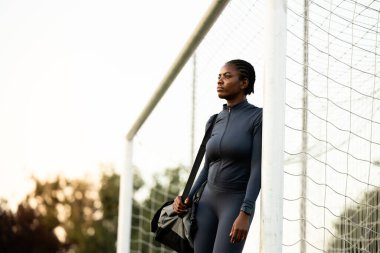 Kadın kaleci kale direğinde durup antrenman yapmayı düşünüyor. Futbol sporu.