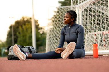 Siyah kadın koşucu ya da sporcu vücut çalışıp antrenmandan önce ısınıyor..