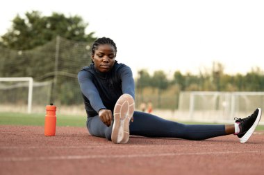 Siyah kadın koşucu ya da sporcu vücut çalışıp antrenmandan önce ısınıyor..