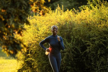 Gün batımında koşan motive olmuş siyah bayan sporcu..