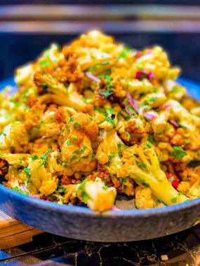 Kızarmış karnabahar, doğranmış maydanoz ve büyük gri tabakta pembe soğan. Bir şenlik, parti ya da düğün organizasyonunda