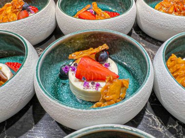 milk mousse or panna cotta - boiled cream - is northern Italian dessert made from cream, sugar, gelatin and vanilla, garnished with caramelized sugar, strawberries and blueberries. buffet. catering