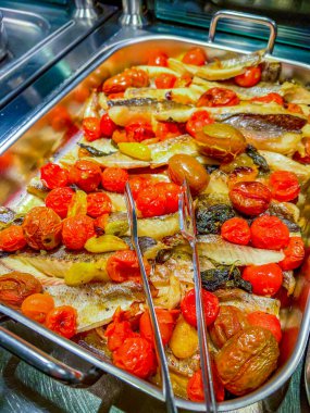 Stewed fish with tomatoes in a large iron bowl. at catering event on some festive event, party or wedding reception. buffet.