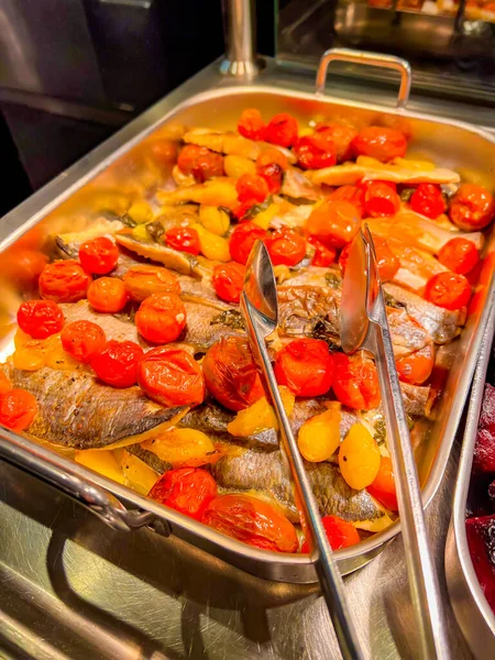 Stewed fish with tomatoes in a large iron bowl. at catering event on some festive event, party or wedding reception. buffet.