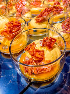 Exotic mousse, served with mango sauce, garnished with caramelized sugar, grape halves in a glass bowl. buffet. catering