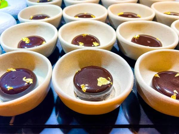 Chocolate mousse, decorated with edible gold, is thinnest foil made of precious metals, which has neither taste nor smell. at catering event on some festive event, party or wedding reception. buffet.