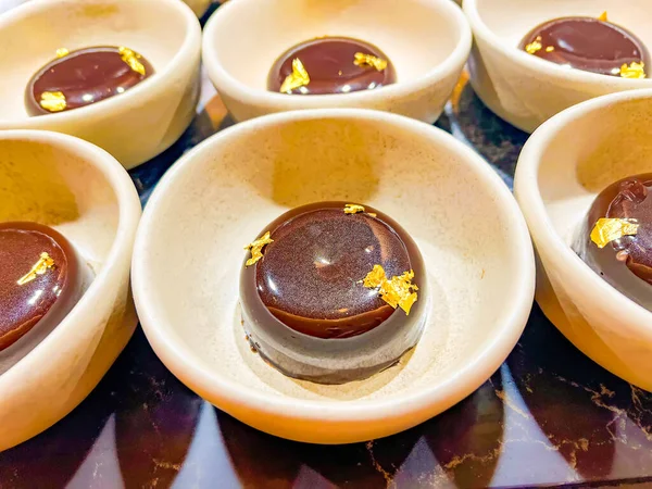 Chocolate mousse, decorated with edible gold, is thinnest foil made of precious metals, which has neither taste nor smell. at catering event on some festive event, party or wedding reception. buffet.