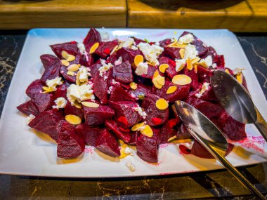 Baked beets with goat cheese, thin slices of almonds on a white square dish. at catering event on some festive event, party or wedding. Buffet catering