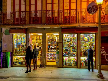 Porto, Portugal - December 6, 2022: Sale of alcoholic drinks in a shop on one of the tourist streets of the city of Porto, Portugal. Glowing shop windows at night