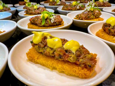 mini bruschetta with tartar, garnished with thick sauce. at catering event on some festive event, party or wedding. buffet