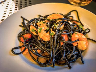Black linguine with boiled shrimps and tomatoes