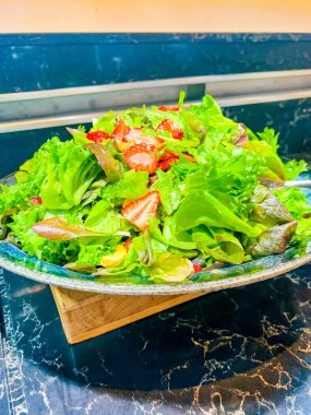 Farklı türde marul, dilimlenmiş çilek dilimlenmiş üzüm, gri tabakta fındık. Bir şenlik, parti ya da düğün organizasyonunda