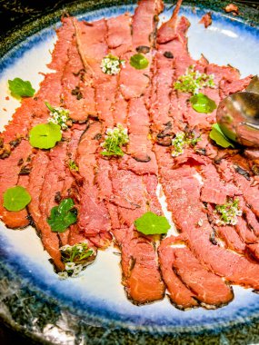 on a large plate thinly sliced pieces of meat - veal, decorated with ecological flowers. at a catering event at some festive event, party or wedding