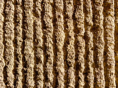 Bükülmüş beton yüzey. Beton çizgili yüzeyin açık hava görüntüsünü kapatın. Gölgeli kaba gri bir dokunun soyut tasarımı. Modern bir bina duvarının ayrıntıları. Desen