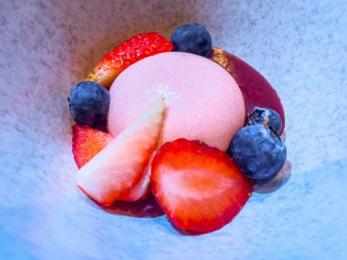 Dilimlenmiş çilek, yaban mersini ve gri bir tabakta tatlı sosla süslenmiş çilek. Yemek organizasyonunda bir şenlik, parti ya da düğün resepsiyonunda