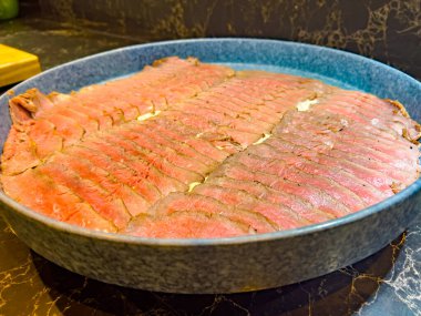 on a large plate thinly sliced pieces of meat - veal, decorated with ecological flowers. at a catering event at some festive event, party or wedding