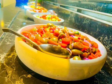 Kırmızı domates salatası, pembe soğan ve siyah bir masada büyük gri bir tabakta maydanoz. Açık büfe. Yemek organizasyonunda bir şenlik, parti ya da düğün resepsiyonunda