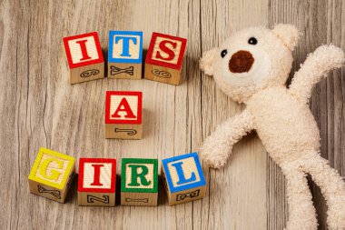 A Baby Shower invitation for a baby girl on wooden background
