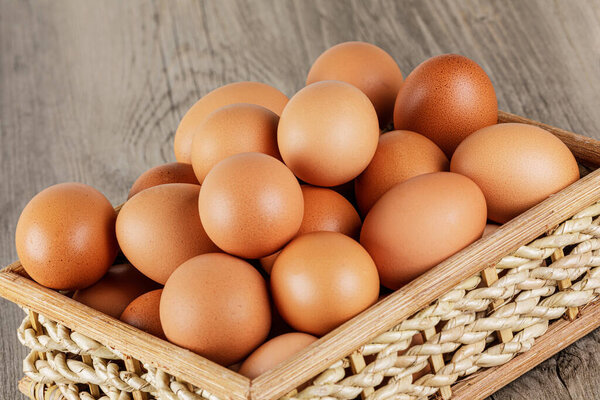Close up of a Basket of fresh raw Brown Eggs with a wooden background and copy space