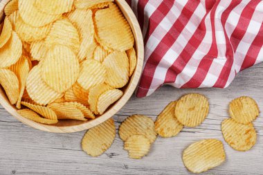 Tahta zemin üzerinde büyük bir kase Çedar ve Ekşi Kremalı Patates cipsi ve fotokopi alanı olan düz bir zemin.