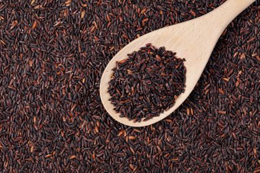 Tahta kaşık ve fotokopi alanı ile izole edilmiş lezzetli siyah pirinçten düz bir şekilde uzan.