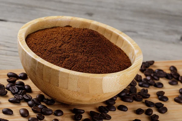 Close up of a wooden bowl of Fresh Ground Coffee isolated on a wooden background with copy space