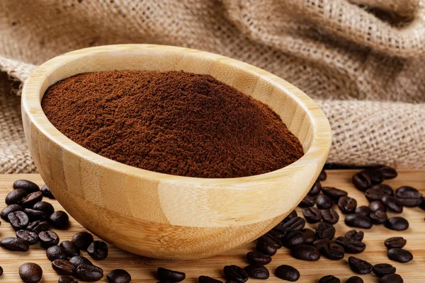 Close up of a wooden bowl of Fresh Ground Coffee isolated on a wooden background with copy space