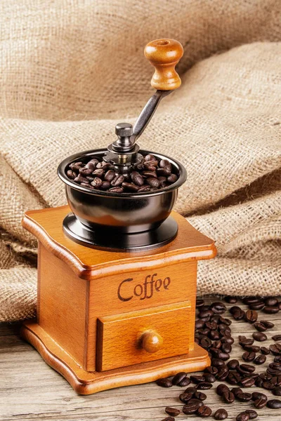 A Vintage Coffee Grinder isolated on a wooden table with a burlap back ground and copy space