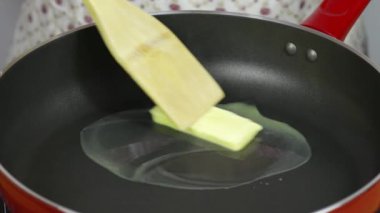 Eriyen tereyağını kapat. Mutfaktaki ocağın üstünde bir tava var.