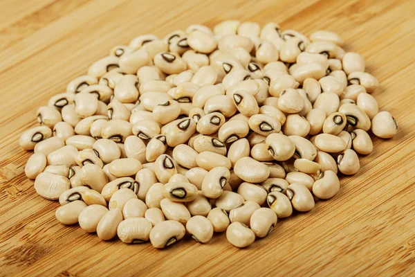 Close up of a pile of Black Eyed Peas also known as Black Eyed Beans on a wooden background with copy space